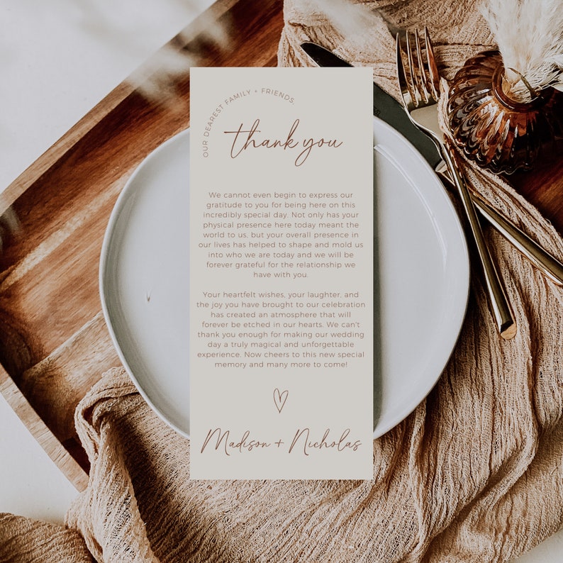 May include: A thank you card with a brown background and white text. The card says "Our Dearest Family & Friends, Thank You" and includes a message of gratitude for the guests' presence at the wedding. The card is signed "Madison + Nicholas".