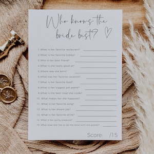 May include: A white printable bridal shower game card with the text "Who knows the bride best?" and 15 questions about the bride. The card has a black heart symbol and a score of 15.