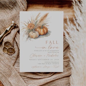 May include: A fall-themed engagement party invitation featuring a watercolour illustration of pumpkins and wheat stalks. The invitation is on a light grey background with the text "Fall in love" in a copper colour. The text "kindly join us for an engagement party honouring Clarissa + Nicholas" is in a black font. The date and location of the party are listed below. The invitation is registered on Amazon and Target.