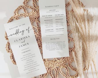 May include: Two white wedding programs with black text, one reading "Welcome to the wedding of Clarissa and James." The other program lists the wedding party and a thank you message. The programs rest on a woven placemat with dried pampas grass.