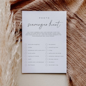 May include: A white card with black text that says "PHOTO Scavenger Hunt". The card has a list of items to photograph at a wedding, such as "the bride laughing", "a baby", "somebody with a pink shirt", "a silly selfie", "a group of friends", "a gift", "a selfie with a bridesmaid", "the flowers", "the dessert", "something blue", "a hug", "selfie with the bride", "someone making a toast", "the best dancer", "the decor", and "the bride's ring".