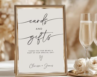 May include: A gold-framed sign with white background and black text that reads "cards and gifts". The sign also includes the text "Thank you for being a part of our special day!" with a small heart symbol and the names "Clarissa + James".
