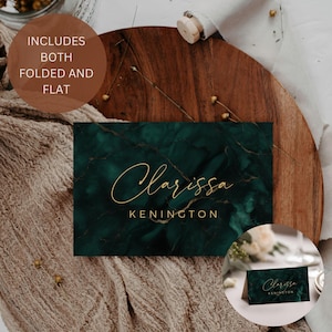 Puede incluir: Tarjeta de mesa verde esmeralda con texto dorado en cursiva que dice "Clarissa" y "Kenington". La tarjeta tiene una textura de mármol y se muestra plana y plegada. El texto "INCLUDES BOTH FOLDED AND FLAT" está en un círculo marrón.