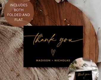 Könnte beinhalten: Schwarze Dankeskarte mit goldener Aufschrift "thank you" mit einem Herz und "MADISON + NICHOLAS". Die Karte liegt auf einer Holzoberfläche.