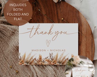 May include: A thank you card with the words "thank you" in a handwritten style, a small heart, and the names "Madison + Nicholas." The card features a floral design at the bottom and includes both folded and flat options.