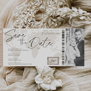 May include: A save the date card with a world map background and a photo of a couple. The text reads "Save the Date" and "Pack Your Bags Destination Love". The card also includes the couple's names, wedding date, and website.