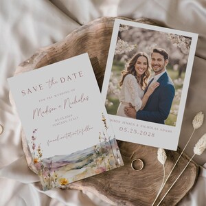 May include: Save the date card with a watercolor landscape background and floral accents. The card features the text "Save the Date" in a script font, followed by "For the Wedding of" and the names "Madison + Nicholas". The date "05.25.2028" and location "Tuscany, Italy" are also included. The text "formal invitations to follow" is at the bottom of the card.