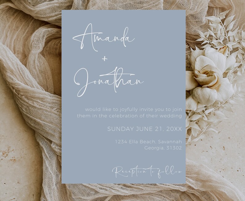 May include: A light blue wedding invitation card with white text. The card announces the wedding of Amanda and Jonathan on Sunday, June 21st. The invitation includes the wedding location: 1234 Ella Beach, Savannah, Georgia, 31302. The text "Reception to follow" is at the bottom of the card.