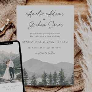 May include: Wedding invitation with a watercolor mountain landscape background. The invitation is for Amelia Adams and Graham Jones, and it states the wedding will be held on Sunday, June 21, 20XX at 10:00 AM. The address is 1234 Main St Driggs, ID 73819. The invitation also states that the reception will follow.