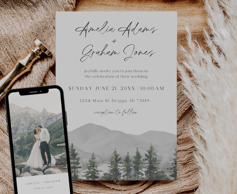 May include: Wedding invitation with a watercolor mountain landscape background. The invitation is for Amelia Adams and Graham Jones, and it states the wedding will be held on Sunday, June 21, 20XX at 10:00 AM. The address is 1234 Main St Driggs, ID 73819. The invitation also states that the reception will follow.