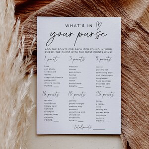 K&ouml;nnte beinhalten: Eine wei&szlig;e Karte mit dem Text "What's in your purse?" in schwarzer Kursivschrift. Die Karte ist ein Spiel, bei dem die G&auml;ste Punkte f&uuml;r Gegenst&auml;nde sammeln, die sie in ihren Handtaschen finden. Die Gegenst&auml;nde sind in Kategorien mit Punktwerten aufgelistet: 1 Punkt, 3 Punkte, 5 Punkte, 10 Punkte, 15 Punkte und 20 Punkte.