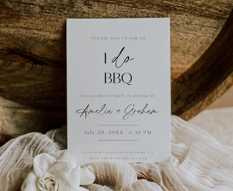 May include: A white invitation card with black text announcing an "I do BBQ" engagement party for Amelia and Graham on July 28th, 20XX at 6:30 PM. The card includes the address and RSVP information.