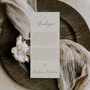 May include: A thank you card with a brown background and white text. The card says "Dearest Family & Friends, Thank You" and includes a message of gratitude for the guests' presence at a wedding. The card is signed "Madison + Nicholas".