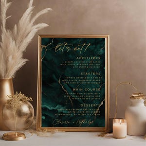 May include: A green and gold wedding menu with a marble background. The menu lists appetizers, starters, main course, and desserts. The text "let's eatt" is written in gold script at the top of the menu. The names Clarissa and Nicholas are written at the bottom of the menu.
