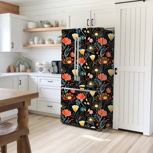 May include: A white kitchen with a refrigerator featuring a floral pattern wallpaper with red, orange, yellow, and blue flowers on a black background.