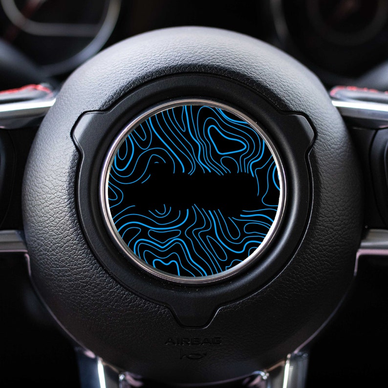 May include: A black leather steering wheel with a blue and black patterned design in the center.
