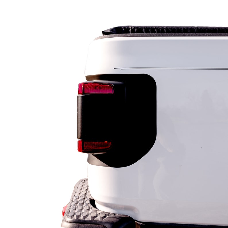 May include: White pickup truck bed with a black tonneau cover and a red taillight. The truck bed is clean and has a smooth surface.