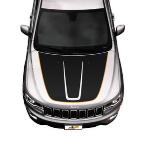 May include: A silver Jeep with a black and orange hood decal. The decal has two black stripes with a white stripe in the center. The Jeep has a black grille with the word "Jeep" in white letters.