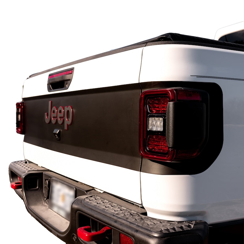 May include: White Jeep truck with a black tailgate and red taillights. The Jeep logo is visible on the tailgate.