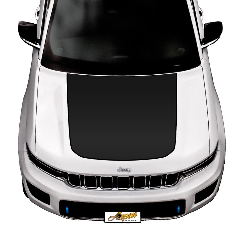 May include: A white Jeep with a black hood wrap. The Jeep has a black grille with the word "Jeep" in silver lettering. The front bumper has two blue lights on either side of the number plate.
