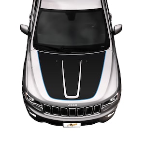 May include: A silver Jeep with a black and blue hood decal. The decal has a white stripe down the center and blue stripes on the sides. The Jeep has a black grille with the word "Jeep" in white letters.