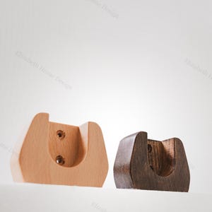 May include: Two wooden wall mounted shelf brackets. One is light brown and the other is dark brown. Both have a curved shape and are designed to hold a shelf.