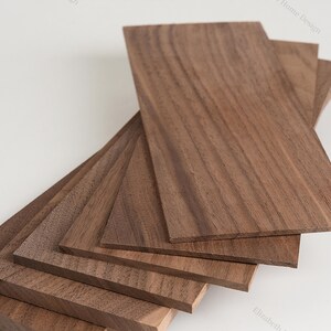 May include: A stack of six thin, rectangular pieces of walnut wood. The wood has a rich brown color and a natural grain pattern.
