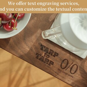 May include: A wooden cutting board with the text "TARP to TARP 0/0 neru design works" engraved on it. A white coffee maker and a bowl of cherries are on the board.