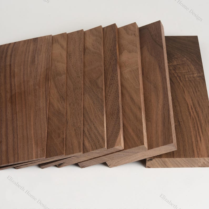 May include: A stack of eight wooden boards, all the same size and shape, made of dark brown walnut wood. The boards are arranged in a staggered pattern, with the top board slightly overlapping the one below it.
