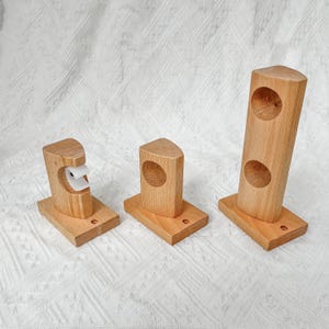 Puede incluir: Tres soportes de pared de madera con recortes circulares. Los soportes son de diferentes tamaños y están hechos de madera marrón claro.