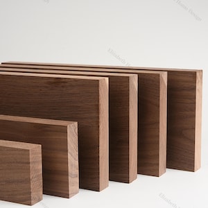 May include: A set of six wooden boards in various sizes, all made of dark brown walnut wood. The boards are arranged in a staggered pattern, with the largest board at the back and the smallest board at the front.