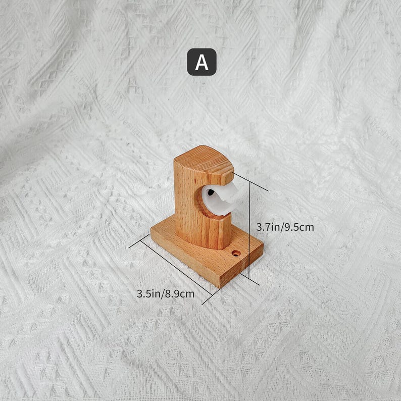 May include: A wooden wall mount hook with a white plastic ring. The hook measures 9.5cm by 8.9cm.