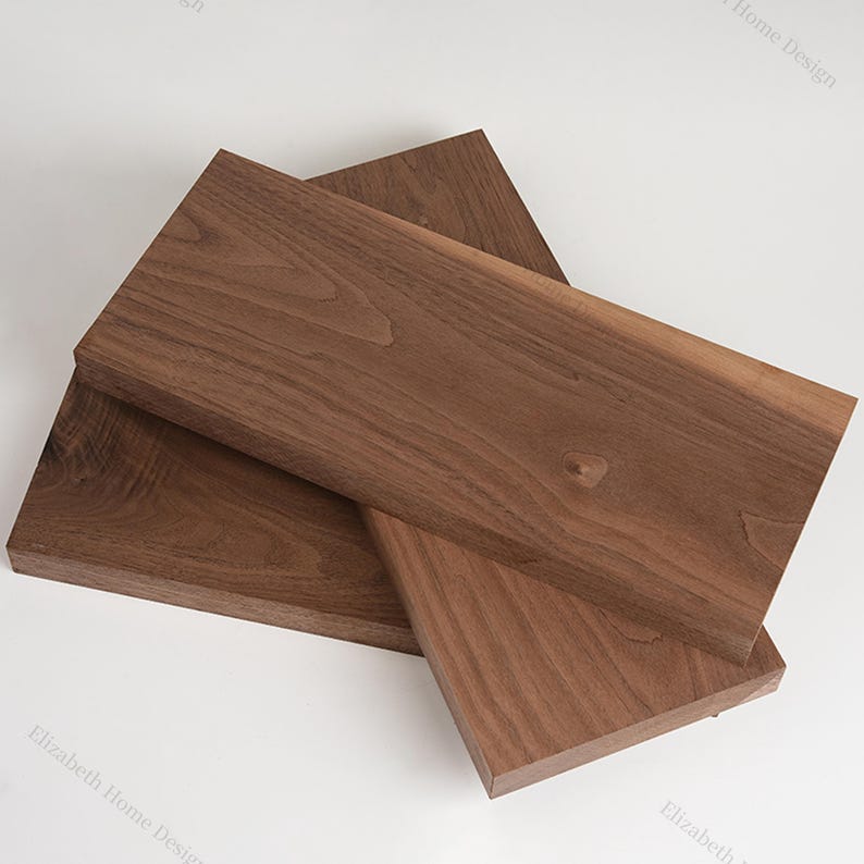 May include: Three pieces of unfinished walnut wood, stacked on top of each other. The wood has a rich brown color and a natural grain pattern.
