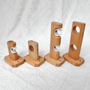 Peut inclure: Quatre supports de tringle à rideau en bois avec des anneaux en plastique blanc. Les supports sont de tailles différentes et sont disposés en rangée du plus petit au plus grand.