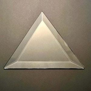 Puede incluir: Un triángulo de vidrio transparente con bordes biselados.