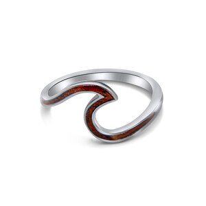May include: A silver ring with a wave design. The wave is made of wood with a reddish-brown color.