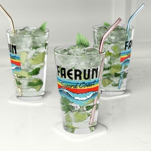 May include: Three clear glass tumblers with colorful graphic designs and straws. The tumblers are filled with ice and a green beverage. The designs feature the words "Faerun Sword Coast" and "Come for the adventure, stay for the loot".