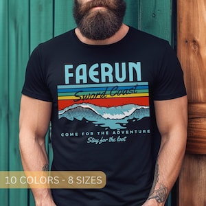 May include: A black t-shirt with a retro-style graphic design featuring the text "FAERUN Sword Coast" in blue and white. The graphic also includes a colorful rainbow stripe and a blue wave design. The text "COME FOR THE ADVENTURE Stay for the loot" is printed below the graphic. The shirt is available in 10 colors and 8 sizes.