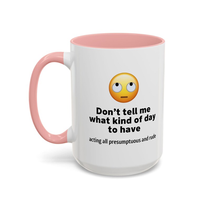 以下が含まれることがあります： ピンクの縁取りが付いた白いセラミック製のコーヒーカップ。カップには、混乱した表情の黄色い絵文字と、「生意気な態度で、どんな一日を過ごすべきか言うな」というテキストが書かれています。