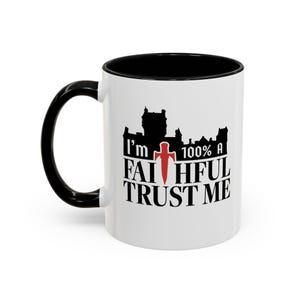 May include: White ceramic coffee mug with a black rim and handle. The mug features a black silhouette of a castle with the text "I'm 100% a Faithful Trust Me" in black lettering with a red cross.