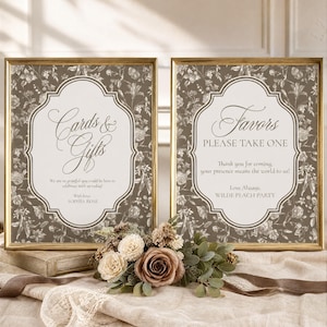 May include: Two gold-framed signs with a dark brown floral background and white center panels. The left sign reads Cards & Gifts, We are so grateful you could be here to celebrate with us today!, With Love, SOPHIA ROSE. The right sign reads Favors, PLEASE TAKE ONE, Thank you for coming, your presence means the world to us!, Love Always, WILDE PEACH PARTY.