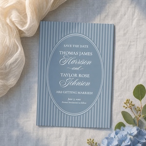 May include: A rectangular Save the Date card featuring a dusty blue background with vertical white stripes. A central white oval frame contains the text: SAVE THE DATE, THOMAS JAMES Harrison and TAYLOR ROSE Johnson ARE GETTING MARRIED! June 7, 20xx.