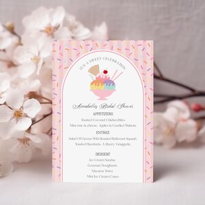 May include: A pink invitation card with a colorful ice cream sundae illustration. The card has a vertical design with text that reads "IT'S A SWEET CELEBRATION" and "Annabelles Bridal Shower". The card lists appetizers, entree, and dessert options.