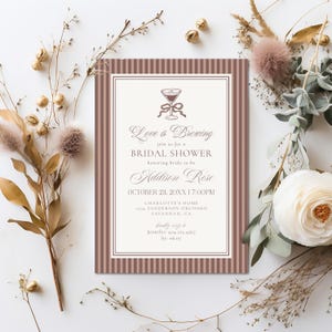 May include: A bridal shower invitation with a cocktail glass illustration and the text "Love is Brewing." The invitation features a striped border in shades of brown and cream, with the name "Addison Rose" and event details.