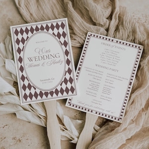 May include: Two wedding fan programs with wooden handles. The left fan has a diamond pattern border and the text "Our Wedding Thomas & Ansley". The right fan lists the order of events and wedding party details.