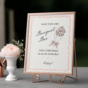 May include: A rose gold framed sign with the text "MAKE YOUR OWN Bouquet Bar" and a bouquet illustration. The sign is on a stand, with a white vase and copper pitcher to the left. The sign reads "PICK A FEW STEMS TO GO ON YOUR WAY. Enjoy!"
