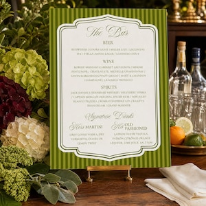 May include: A rectangular bar menu sign with a green and white striped border and a white center panel. The text lists categories including Beer, Wine, Spirits, and Signature Drinks, specifically detailing options like Martini and Old Fashioned.
