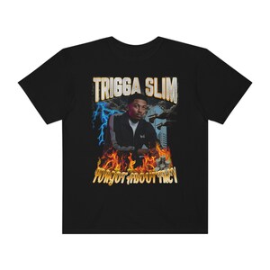 May include: Black t-shirt featuring a graphic of a man with the text "TRIGGA SLIM" above his image. The graphic includes lightning bolts, flames, and the text "FORGOT ABOUT TREY".