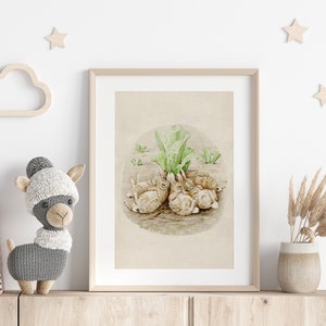 May include: A framed watercolor illustration of a group of brown rabbits huddled together under a green leafy plant. The illustration is on a beige background with a white border. The frame is light brown wood.