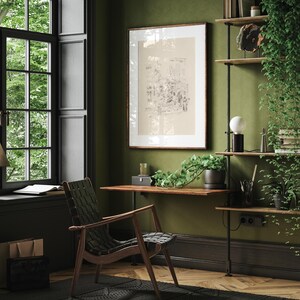 May include: A green room with a wooden desk and a black leather chair. A framed print hangs on the wall above the desk. A shelf with books and plants is on the right side of the image.
